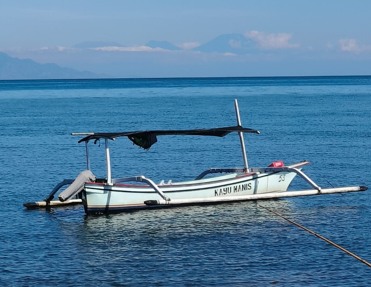 Prahu de pêcheur au mouillage devant Lovina, mer calme et montagnes à l'horizon